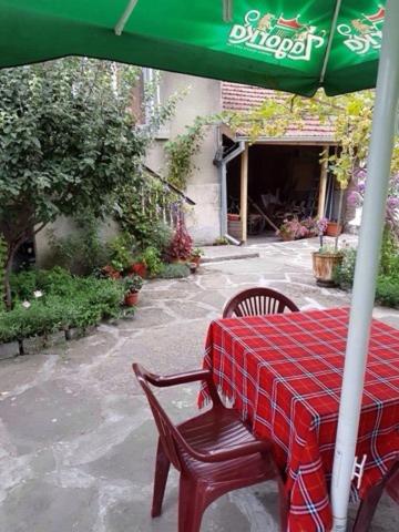 stół z czerwoną tkaniną i zielonym parasolem w obiekcie Къща Чалъкови w mieście Trjawna