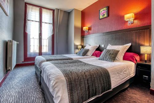 two beds in a hotel room with red walls at Cit'Hotel La Résidence in Nancy