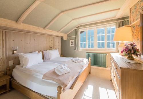 a bedroom with a large white bed and a window at Chalet Irene in Wengen