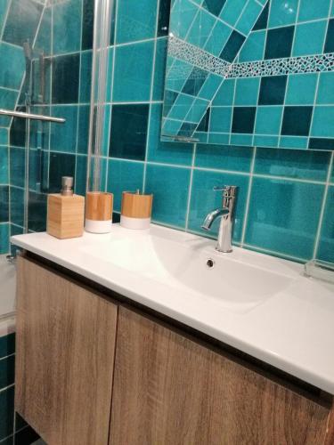 La salle de bains est pourvue d'un lavabo et d'un mur carrelé bleu. dans l'établissement Magnifique deux pièces au calme, à Deauville