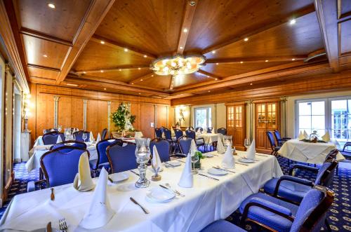 a conference room with tables and chairs and a chandelier at Hotel Landhaus Krombach in Elkenroth