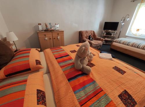 a teddy bear sitting on a bed in a bedroom at Penzion u Krtka in Kraslice
