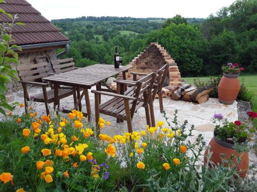 une table et des chaises en bois dans un jardin fleuri dans l'établissement La Belle Âme, à Saint-Priest-des-Champs