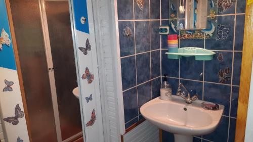 a blue tiled bathroom with a sink and a shower at Šturmų Sodyba in Ventė