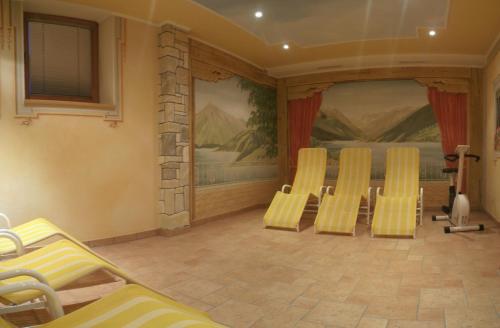 a room with yellow chairs and a wall with paintings at Apart Tuxertal in Finkenberg