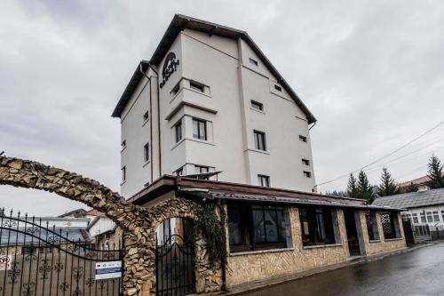 a white building on a street with a fence at Hotel Carpati in Gura Humorului
