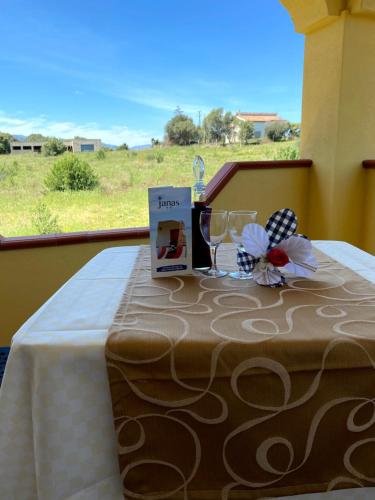 a table with a book and wine glasses on a balcony at Janas B&B in Posada