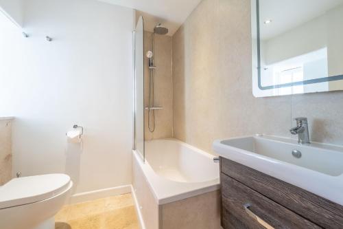 a bathroom with a sink and a toilet and a tub at Cob Cottage in St. Agnes