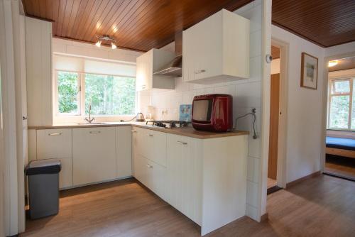 eine Küche mit weißen Schränken und einem roten TV auf der Theke in der Unterkunft Bungalowpark Vogelenzang in Lage Mierde