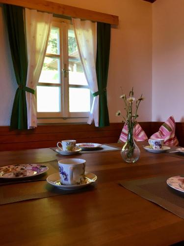 a table with plates and cups and a vase with flowers at Ferienhaus Trausibauer in Stainz