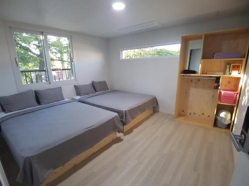 a bedroom with two beds and two windows at Yong Stay in Jeju