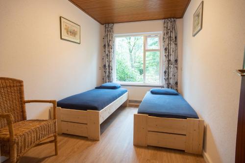 2 Betten in einem Zimmer mit einem Fenster und einem Stuhl in der Unterkunft Bungalowpark Vogelenzang in Lage Mierde