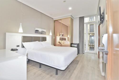 a white bedroom with a large bed and a window at Pensión Alemana in Donostia-San Sebastián