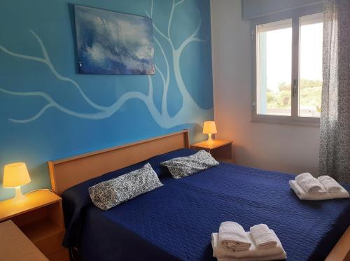 a blue bedroom with a bed with two pillows at Residence Le 4 Stagioni in Menfi