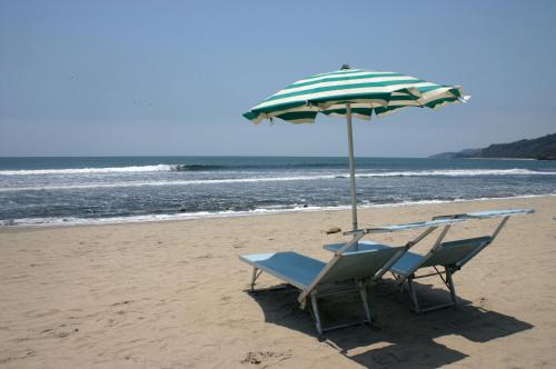 a pair of chairs and an umbrella on the beach at Junto al Rio Bungalows & Suites in Sayulita