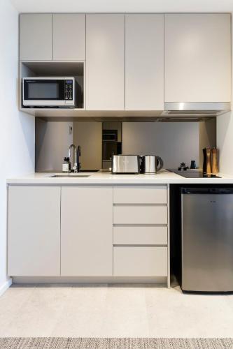 a kitchen with white cabinets and a microwave at Quest Robina in Gold Coast