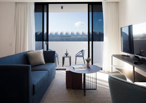 a living room with a blue couch and a television at Quest Robina in Gold Coast