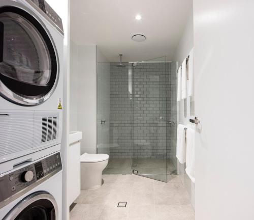 a bathroom with a shower and a toilet and a washing machine at Quest Robina in Gold Coast