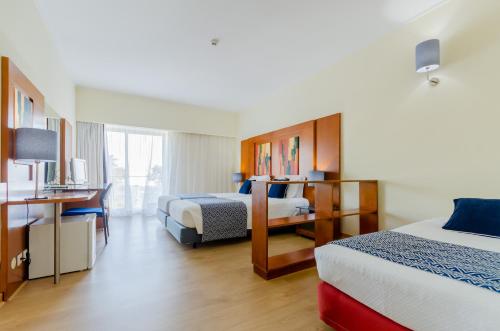 a hotel room with two beds and a desk at Hotel Alvorada in Estoril