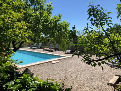 una piscina con sedie e alberi in un cortile di Les intérieurs d'Angèle a Pernes-les-Fontaines