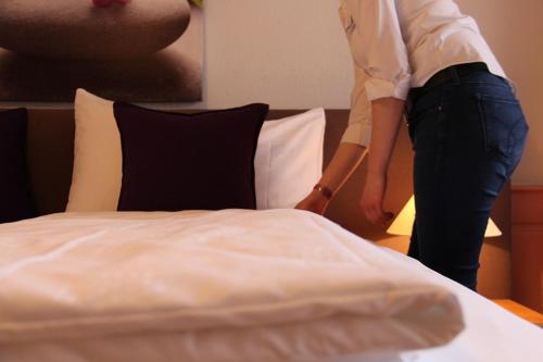 a woman is standing next to a bed at Zum Schwarzen Löwen in Altdorf