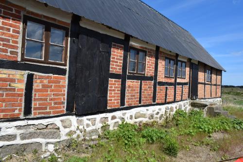 an old brick building with windows and a black roof at Rörums Gårdshotell in Simrishamn