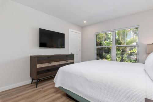a white bedroom with a bed and a television at Escape Coastal Resort on Casey Key in Nokomis