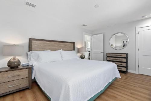 a white bedroom with a large bed and a mirror at Escape Coastal Resort on Casey Key in Nokomis