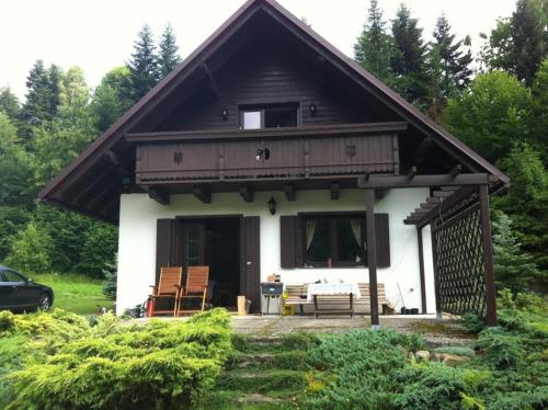 a small house with a porch and chairs in front of it at WISŁA-DOM PRZY RZECE in Wisła