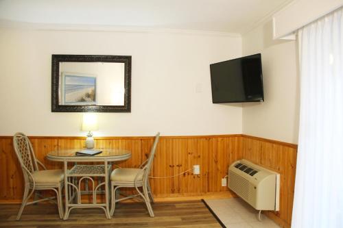 a room with a table and a tv and a table and chairs at Surf Side Hotel in Nags Head