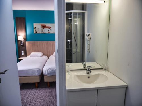 a bathroom with a sink and a bedroom with a bed at Contact Hotel Le Seino Marin - Cléon Elbeuf in Cléon
