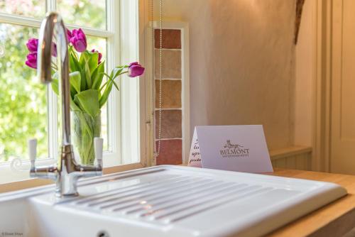 eine Küchenspüle mit einer Vase aus Blumen neben einem Fenster in der Unterkunft Walnut Tree Cottage by Bloom Stays in Faversham