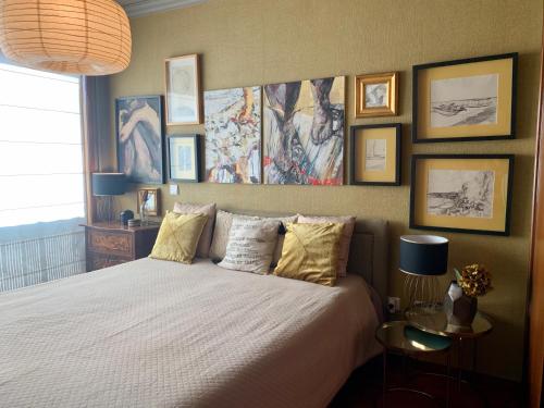 ein Schlafzimmer mit einem Bett und einige Bilder an der Wand in der Unterkunft MimApartment In Front Beach Oporto in Matosinhos