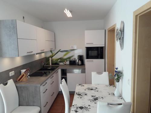 a kitchen with white cabinets and a table and chairs at Apartment Neptun in Ueckeritz