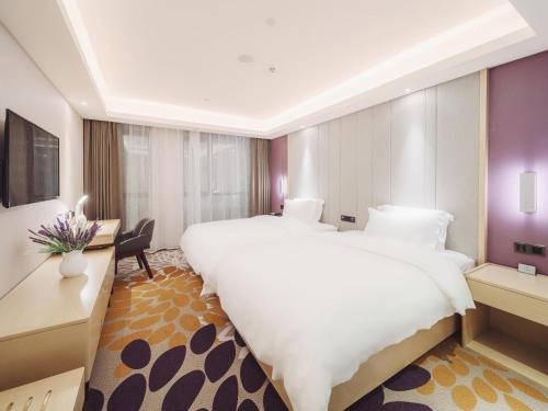 Cette chambre comprend un grand lit et un bureau. dans l'établissement Lavande Hotel Qingzhen Vocational Education City Time Guizhou, à Guiyang