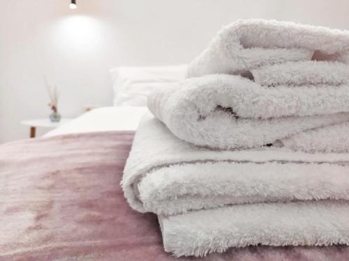 stos białych ręczników siedzących na łóżku w obiekcie ZEN Minimal Luxury Housing Tyros w mieście Tyros