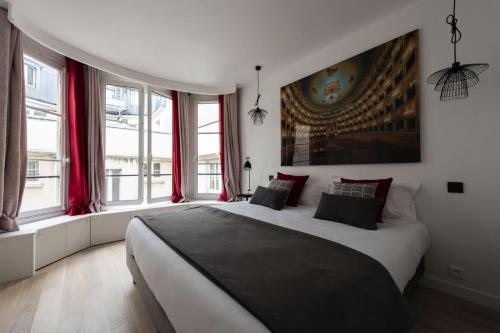 una camera da letto con un grande letto bianco e finestre di Voyageur sans bagage a Parigi