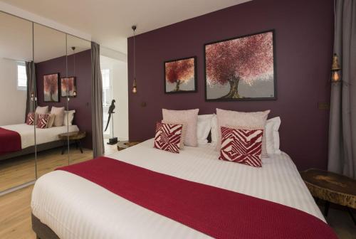 ein Schlafzimmer mit einem großen Bett mit roten und weißen Kissen in der Unterkunft Magnum in Paris