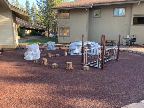 a playground with rocks and logs in front of a house at The Pines at Sunriver in Sunriver