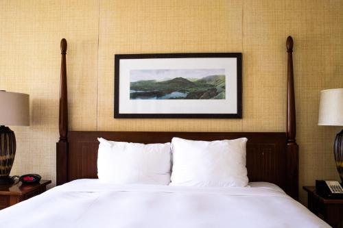 a bed with white pillows and a picture on the wall at Kauai Beach Resort & Spa in Lihue