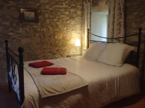 ein Schlafzimmer mit einem Bett mit zwei roten Kissen darauf in der Unterkunft Chambres d´Hôtes Prieuré d'Orniols in Goudargues