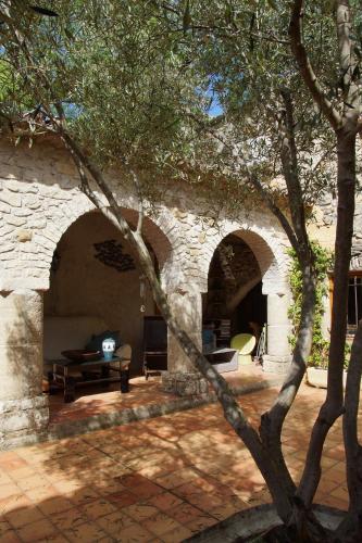 une maison en pierre avec deux arches dans une cour dans l'établissement Chambres d´Hôtes Prieuré d'Orniols, à Goudargues