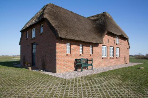 un grand bâtiment en briques avec un toit de chaume dans l'établissement Paulas Haus, à Pellworm
