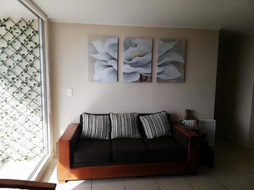 a living room with a couch and three paintings on the wall at Laguna Bahia Algarrobo in Algarrobo