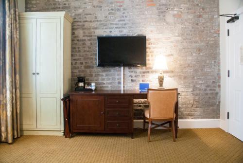 a room with a desk with a television on a brick wall at French Market Inn in New Orleans