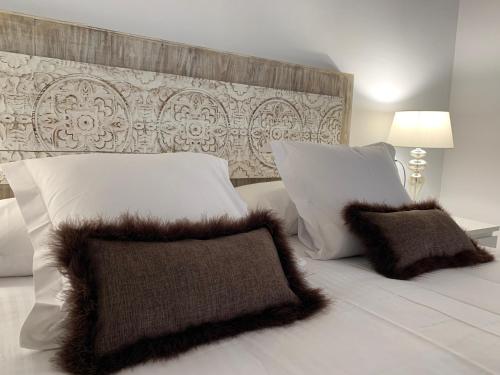 a bed with white pillows and brown cushions on it at Espectacular Tarragona Corsini Apartment-2, en el centro, con parking in Tarragona