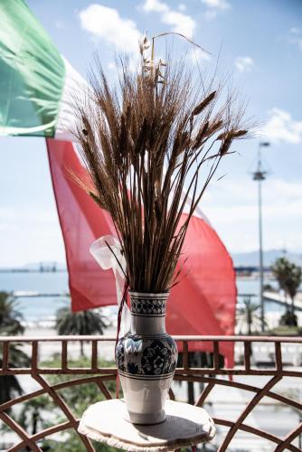 a vase with grass in it sitting on a table at Hotel AeR BJ Vittoria in Cagliari