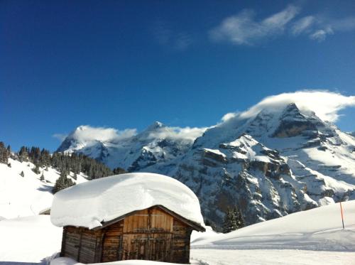 a snow covered hut in front of a mountain at Sam & Cindy Mühlemann in Interlaken