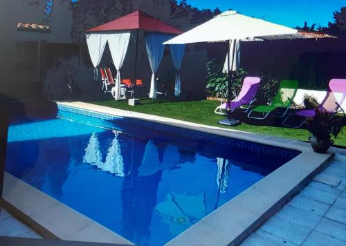 une piscine avec des chaises et un parasol dans l'établissement Villa Provençale, à Arles