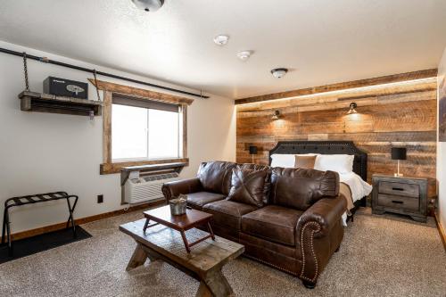 a living room with a leather couch and a bed at The Adventure Inn Yellowstone in West Yellowstone